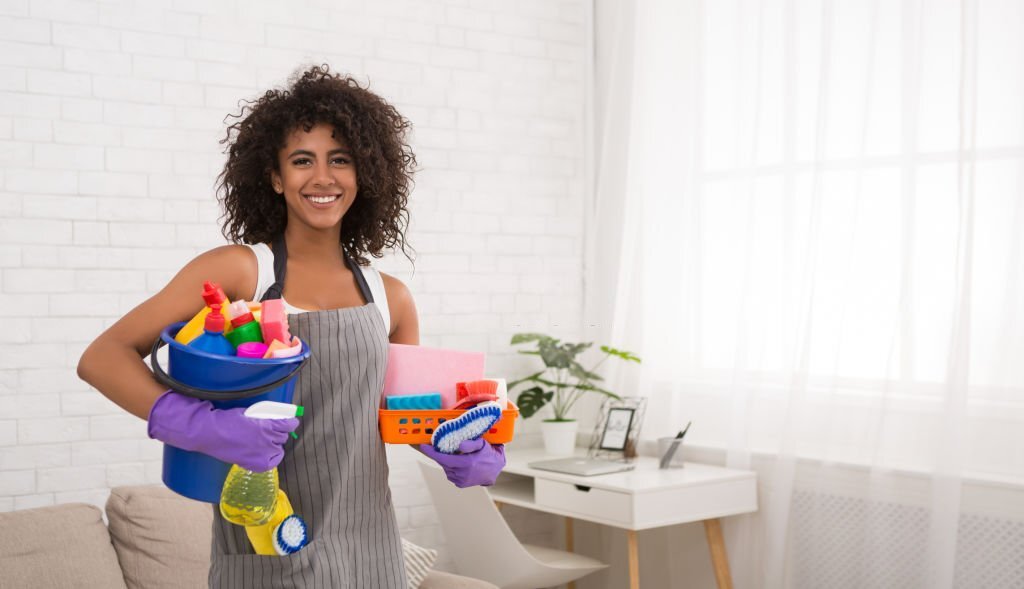 Smiling african-american woman posing with cleaning supplies, housewife preparing detergents for housecleaning, copy space